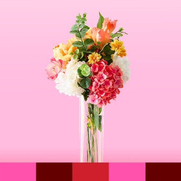 pink, white, green and yellow flowers in clear vase on pink background